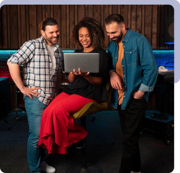 Three middle-aged people, a woman and two men, laughing while looking at a laptop.